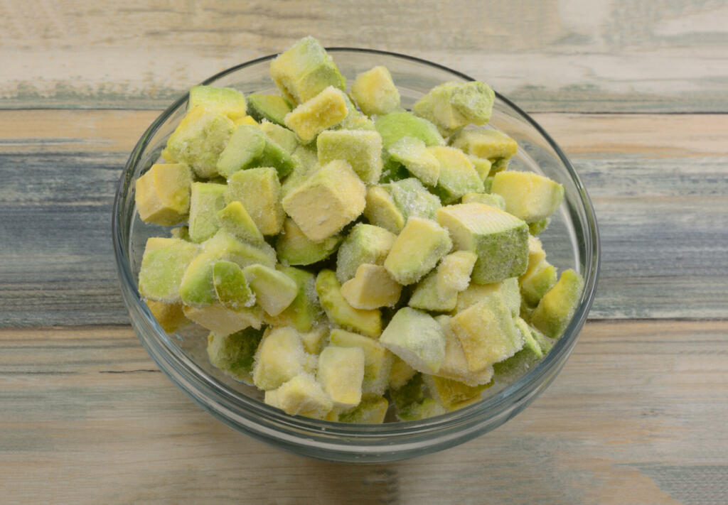 Frozen avocado chunks thawing in glass ingredient bowl on table