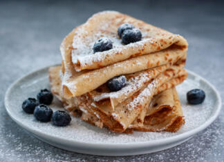 Zgodovina palačink Homemade crepes served with blueberries and powdered sugar on small grey plate
