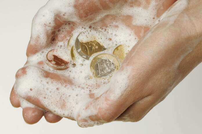 Money laundering illustration. Hand washing coins and ful of foam.