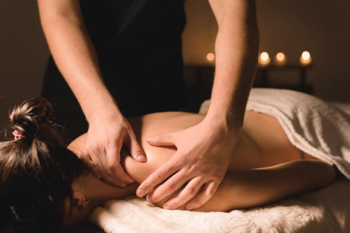 Close up Male manual worker doing spa massage to a young girl in a dark room.