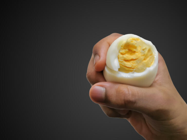 Closeup Image Of Child Holding Sliced Boiled Chicken Egg. Black Isolated Background. Selective Focus