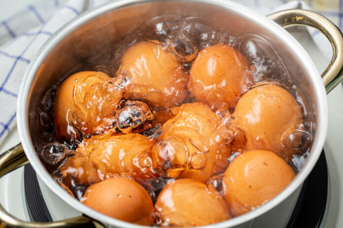 cooking brown chicken eggs in boiling water on electric stove, closeup, elevated view
