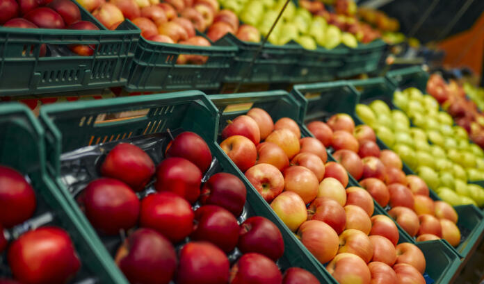 Crates of fresh fruit such as apples are for sale in the store. Buying vegetables and fruits at the market.