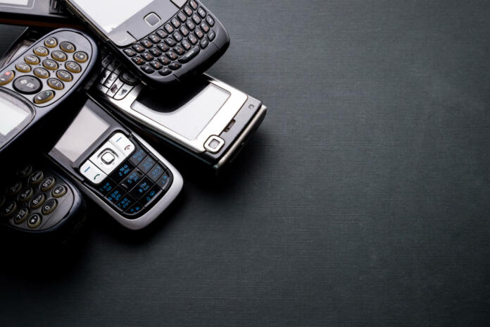 Old and obsoleted cellphones on a black background.