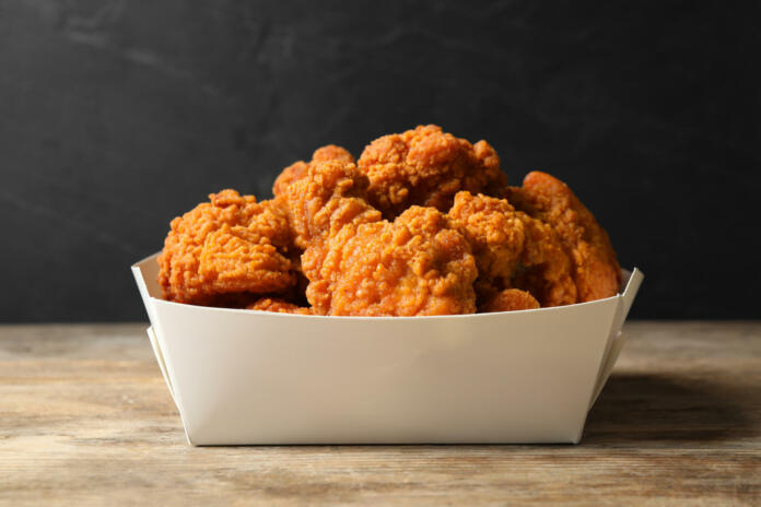 Tasty deep fried chicken pieces on wooden table