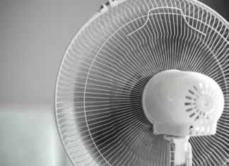 Kako učinkovito ohladiti dom brez klimatske naprave? a close up isolated white ventilator fan at home