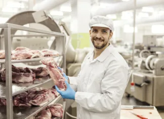 Morda se jim je bolje izogniti! Pet vrst mesa, ki jih mesarji ne bodo kupili v trgovini z živili A meat industry laborer is holding a piece of fresh raw meat and smiling at the camera.