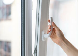 Kako odstraniti kljuko na oknu? (VIDEO) Cropped view of woman holding white modern handle at pvc window with double glazing, opening plastic frame for ventilation her house