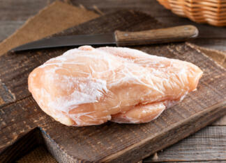 Večna skrivnosti: kako dolgo lahko piščanca hranimo v hladilniku? Frozen chicken fillet on a cutting board on a wooden table. Frozen food