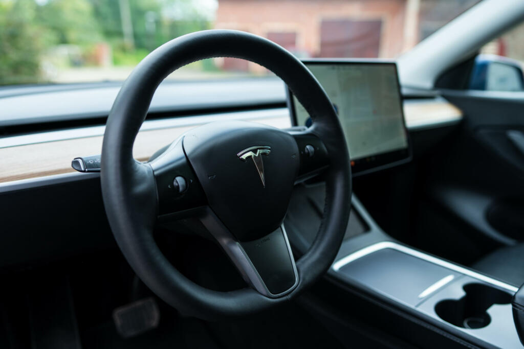 Tesla interior view of dashboard with wooden inlays, modern steering wheel and elegant interface design. Class-leading car model. High quality photo