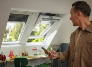 Preverite, kako lahko temperaturo v stanovanju znižate tudi za več kot 5 °C Moški s pametnim telefonom upravlja okno in žaluzije