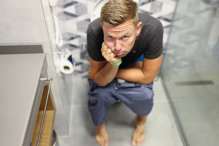 Sad man sits on toilet with bowel problems. Constipation and hemorrhoids concept