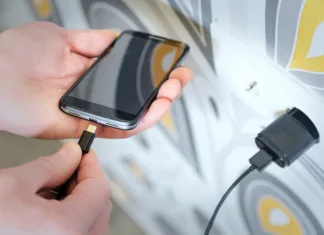 Delate te napake med polnjenjem mobilnega telefona? Skrajšujejo življenjsko dobo baterije … A man is inserting a power cord into the mini USB for charging the smartphone.