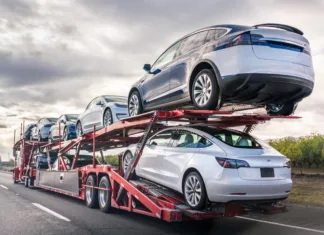 Dec 8, 2019 Bakersfield / CA / USA - Car transporter carries new Tesla vehicles along the interstate to South California, back view of the trailer