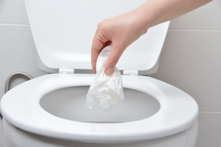 hand of a person who drop tissue paper in the toilet bowl