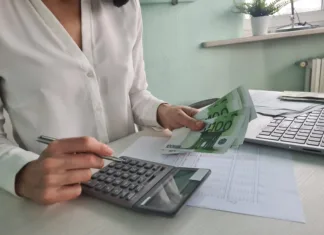 Dobra novica za starše prvošolčkov! Woman is counting on calculator and writing with pen in notebook closeup. Financial budget and payment of taxes