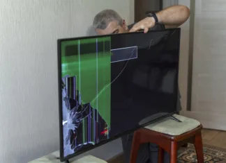 6 stvari, ki jih ne smete početi svojemu TV-ju a man trying to fix a broken TV. device screen is broken