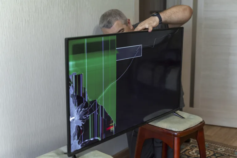 a man trying to fix a broken TV. device screen is broken