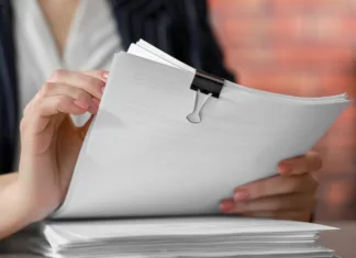 Ne zavrzite jih: to so dokumenti, ki jih boste potrebovali do konca življenja! Woman stacking documents at table in office, closeup