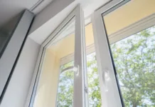 Moderna okna: tehnologija, ki varčuje z energijo low angle view of plastic pvc window with white metal frame installed at modern house, blurred green trees outside the room