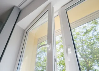 Moderna okna: tehnologija, ki varčuje z energijo low angle view of plastic pvc window with white metal frame installed at modern house, blurred green trees outside the room