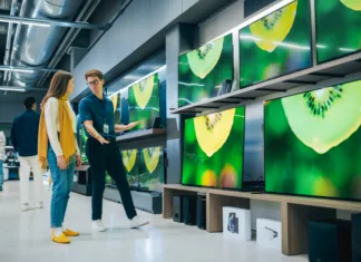 Kaj morate vedeti pred nakupom novega televizorja! Young Female Shopper Having Conversation with Electronics Store Sales Rep. Stylish Lady Explores Sleek Flat-Screen TV Options. Customer Seeking Impressive Television Solutions in Modern Retail Store