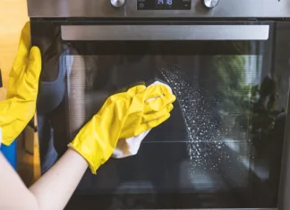 Postavite to posodo v pečico in jo preprosto vklopite! Razlog je, da … Close up of female hand with yellow protective gloves cleaning oven door. young smiling woman in protective glove with rag cleaning oven. Girl polishing kitchen. People, housework, housekeeping, cleaning concept