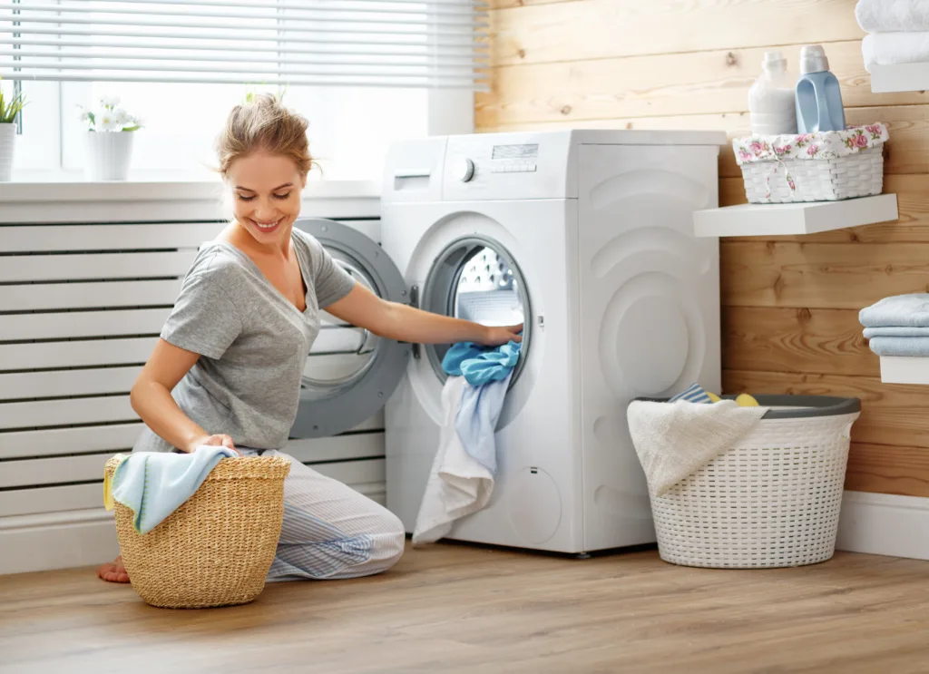 a Happy housewife woman in laundry room with washing machine