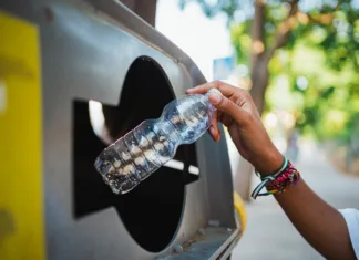 Kako zmanjšati odpadke in izboljšati reciklažo v vsakdanjem življenju? Close up shot of a woman's hand holding a empty plastic bottle to throw it into the trash