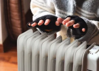10 praktičnih nasvetov za varčevanje z energijo pozimi Person heating their hands at home over a domestic portable radiator in winter