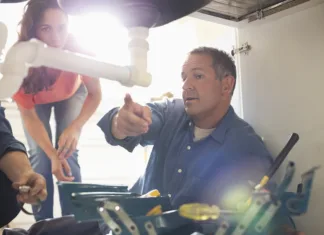 5 skrivnosti, ki vam jih vodovodarji ne bodo razkrili Plumbers working on pipes under sink
