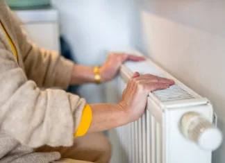 Kako izbrati energetsko učinkovit sistem ogrevanja? Senior woman checking heating radiator in her apartment