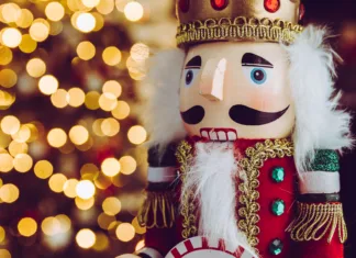 Ste se kdaj vprašali, kakšno povezavo ima Hrestač z božičem? Traditional Christmas nutcracker wooden figure. Beautiful, festive toy soldier, winter holiday season decoration, with tree lights bokeh in background.