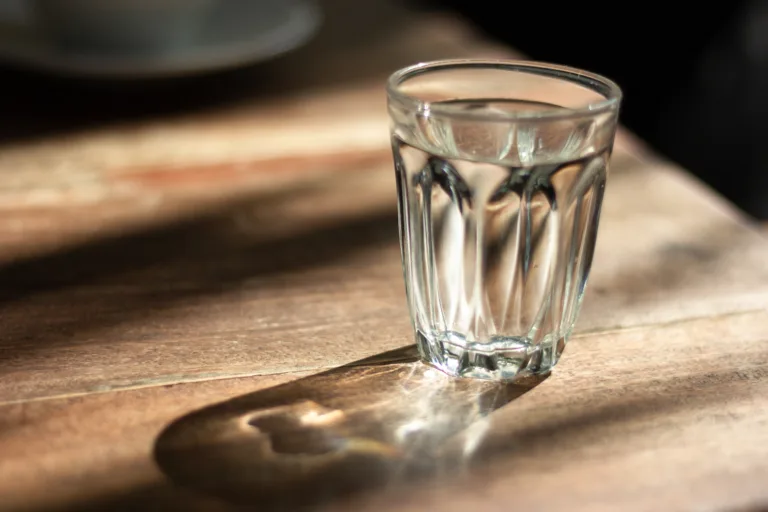 water in glass on wooden table with shadow ,morning sunshine