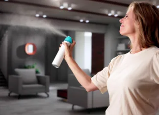 Kako se znebiti vonja po starem? Woman Using Air Spray In Living Room