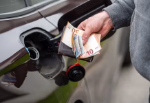 hand of man that puts money into the tank of car, close-up, concept of expensive fuel, fuel crisis