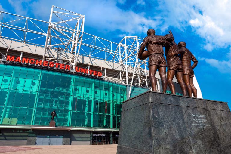 Manchester, UK - May 19 2018: The United Trinity bronze sculpture which composed with George Best, Denis Law and Sir Bobby Charlton in front of Old Trafford stadium