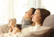 Side view portrait of two roommates relaxing in winter sitting on a sofa in the living room in a house interior