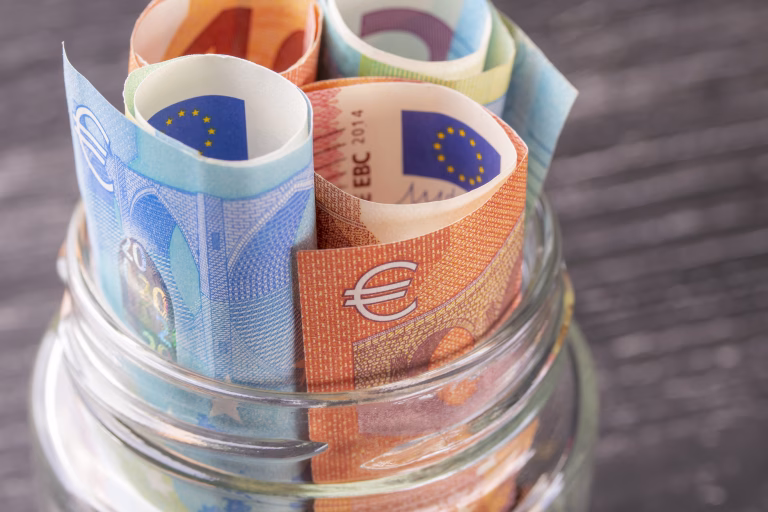 Glass jar with euro bills close-up. View from above. On the old black wooden table. The concept of family and personal savings.