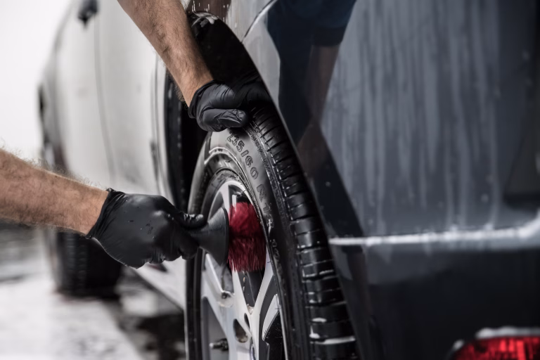 Man cleaning car wheel with brush. Car wash