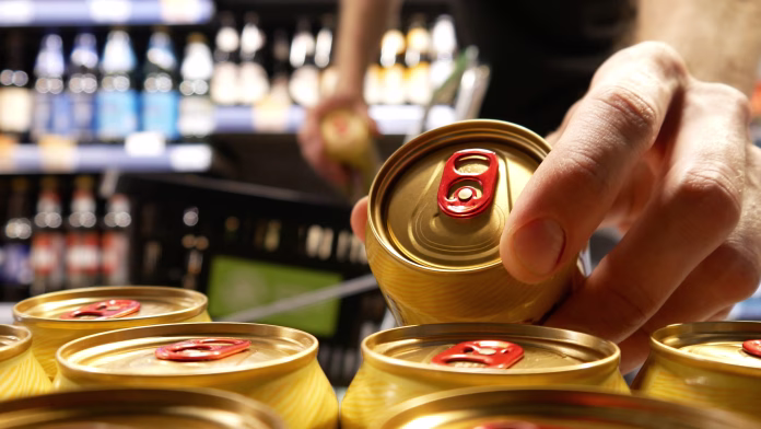 A buyer's hands take two beautiful golden cans of beer and put them into a shopping trolley