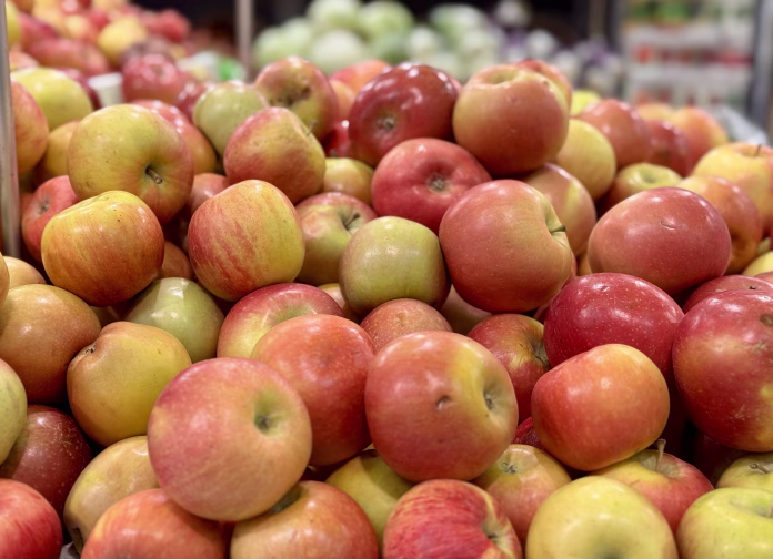 Box filled with fresh natural bio organic red yellow coloured apples placed on counter in local food market. Close-up.