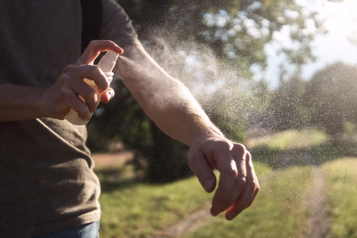Prevention against mosquito bite during sunny summer day. Man is applying insect repellent on his hand.