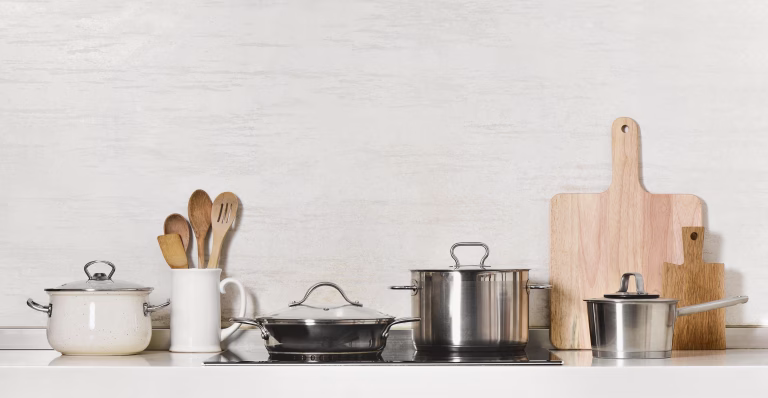 Kitchen utensils and stainless steel cookware front view, space for a text above