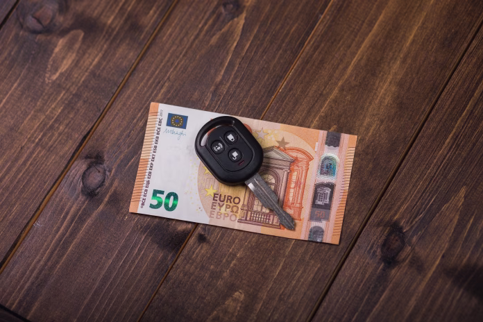 Fifty euros banknote and car keys on wooden background