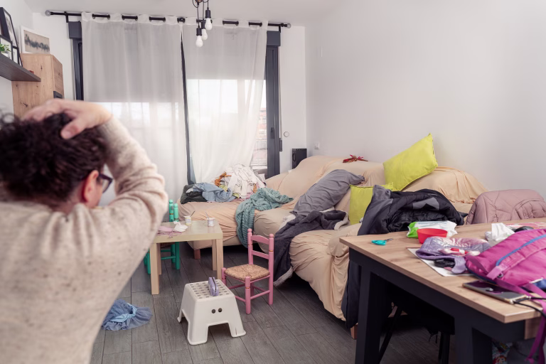 woman with her hands on her head when she sees the mess in her living room