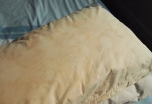 Kako očistiti vzglavnik, ki je povsem porumenel? Dirty pillow from saliva stain on the bed. Dirty pillow with pale yellow and brown color.