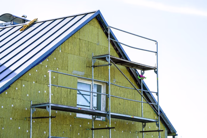 Thermal insulation of the facade of the residential house with thick rock mineral wool slabs using scaffolding