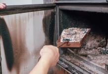 7 načinov, kako uporabiti pepel v dobro vašega doma Fireplace cleaning. A woman's hand holds a shovel with ash in a burnt-out fireplace.