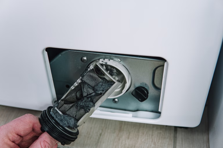 Male hand removes dirty and clogged washing machine pump filter